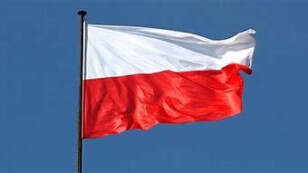 Flaga Polski biało - czerwona zawieszona na maszcie, na tle błękitnego nieba